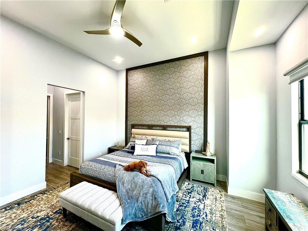 Bedroom featuring a statement accent wall with geometric wallpaper and dark wood trim, recessed lighting, and a modern ceiling fan