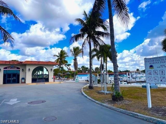 Marina entrance featuring palm trees, a shop with arched windows, and visible boat slips