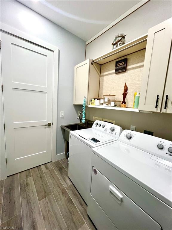 Dedicated utility room featuring wood-finish flooring, a built-in utility sink, upper cabinetry, and a full-size white door with dark hardware