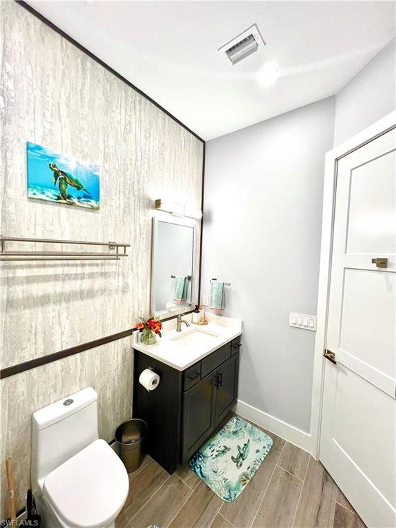 Bathroom featuring a dark wood-finish vanity with a white countertop and integrated sink, a wall-mounted mirror with overhead lighting, and wood-look flooring