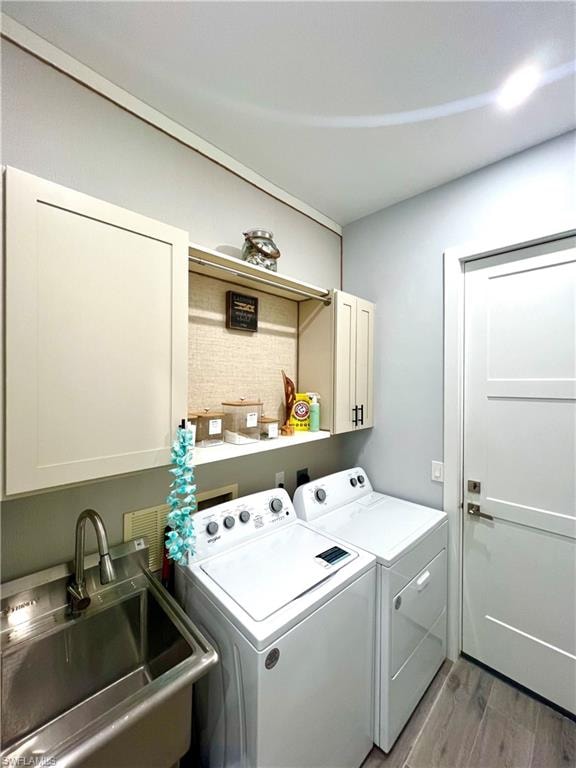 Dedicated laundry room featuring light-toned cabinetry, a stainless steel utility sink with a high-arc faucet, and wood-finish flooring