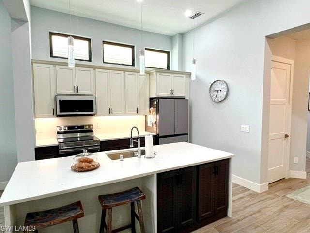Gourmet kitchen featuring a large island with white stone countertops, stainless steel appliances, two-tone cabinetry, and wood-finish flooring