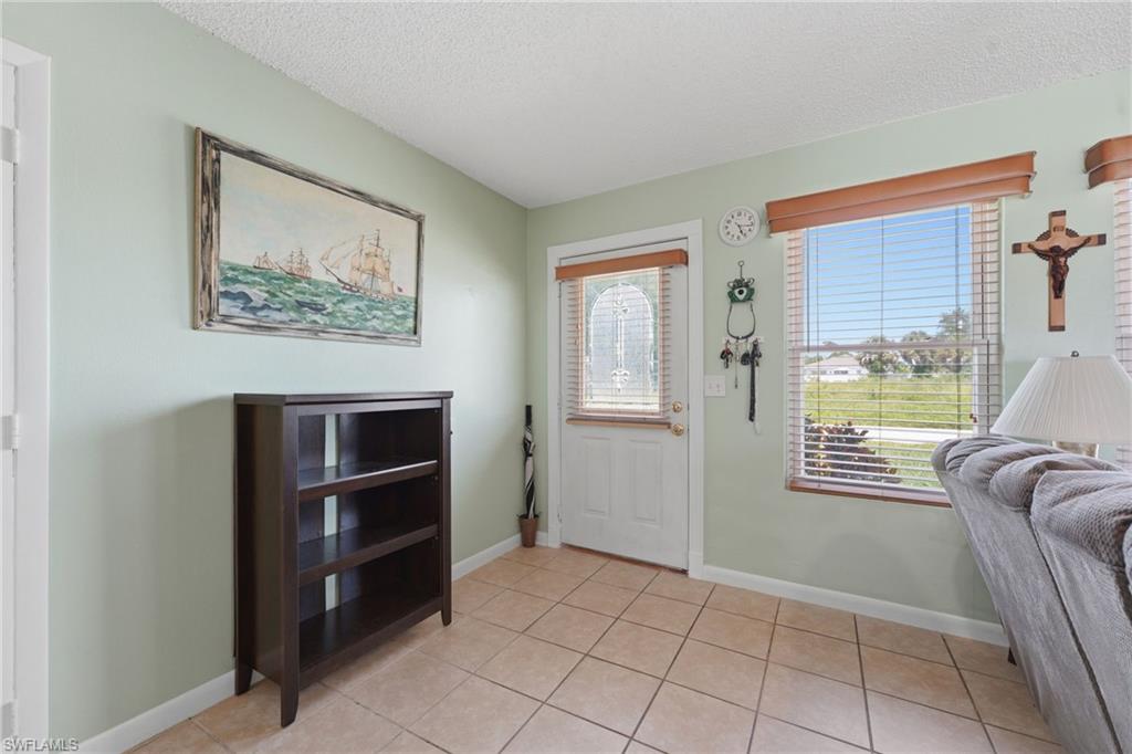 Entryway featuring tiled flooring, a glass-paneled entry door with blinds, and a large window with blinds