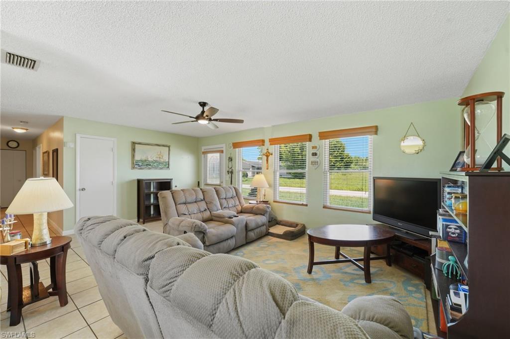 Living area featuring multiple windows with blinds, a ceiling fan with integrated lighting, and light-toned walls
