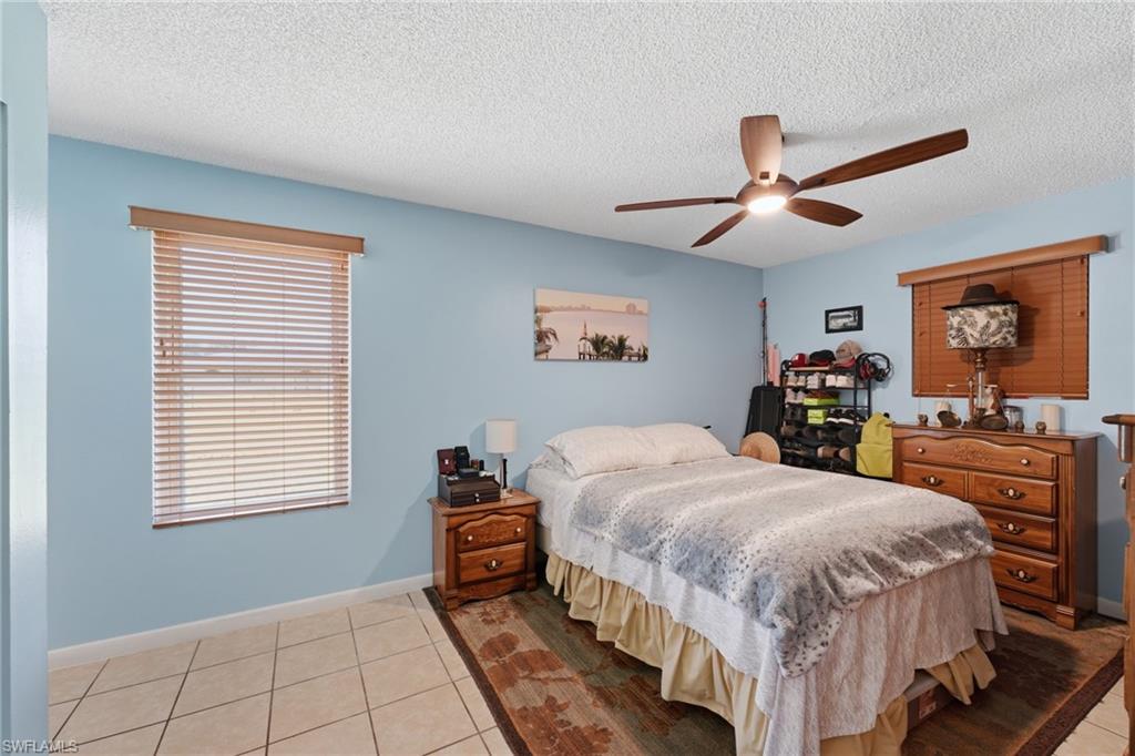 Bedroom featuring tiled flooring, a ceiling fan with integrated lighting, and a window with horizontal blinds