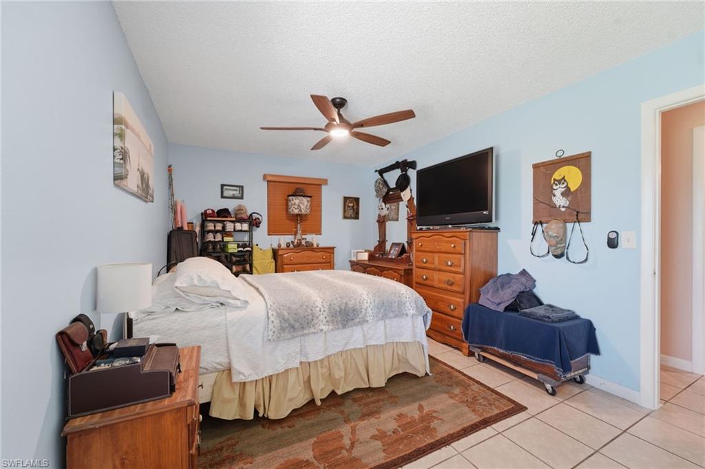 Bedroom featuring light blue walls, tile flooring, a ceiling fan, and a wood-finish window blind