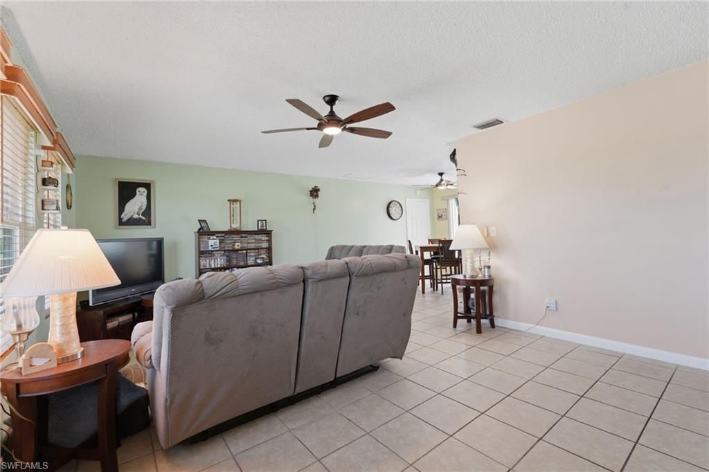Spacious interior with tile flooring throughout, featuring a ceiling fan with integrated lighting and a window with horizontal blinds