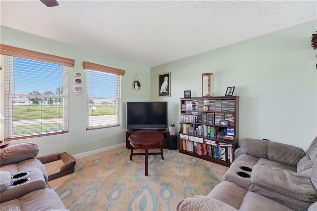 Living area featuring light green painted walls, a textured ceiling, a ceiling fan, and two windows with blinds and wooden valances