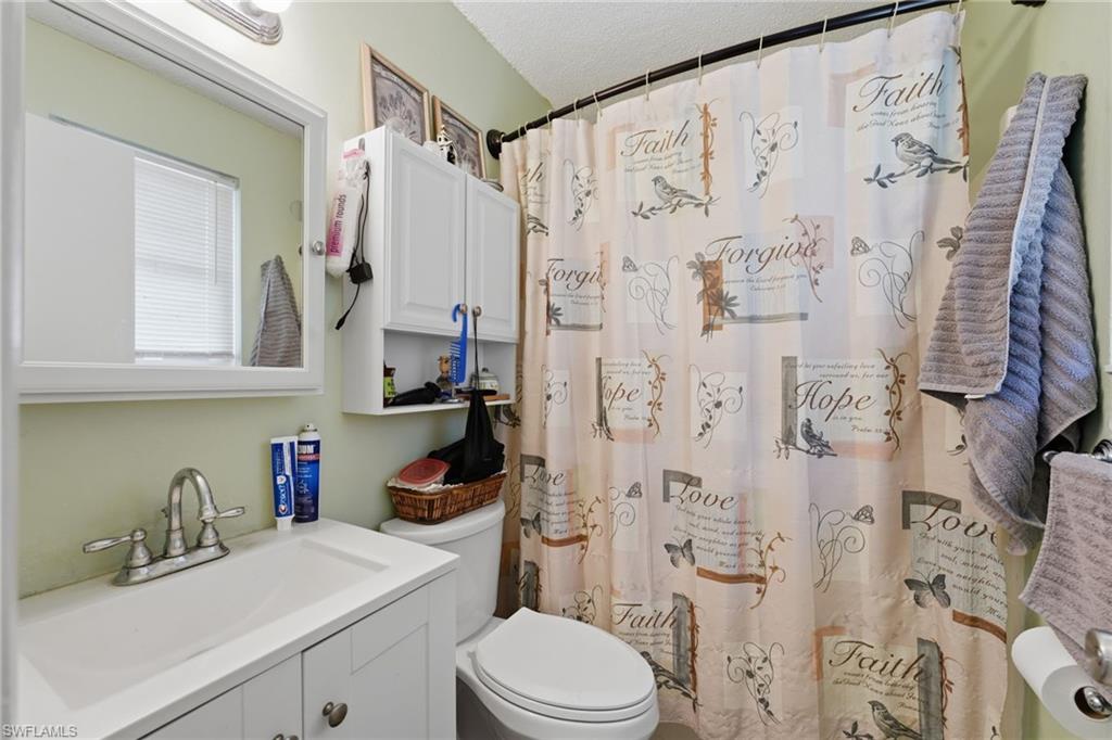Bathroom featuring a white vanity with integrated sink, chrome faucet, and mirrored medicine cabinet