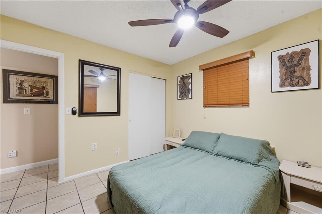 Room featuring tile flooring, a ceiling fan with integrated lighting, and a window with wood-look blinds