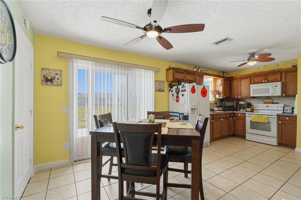 Kitchen featuring wood cabinetry, white appliances, and a tiled backsplash