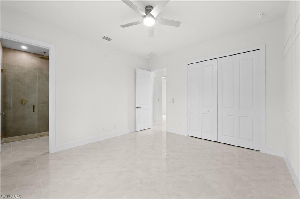 Spacious interior room featuring light-toned large format tile flooring and a ceiling fan