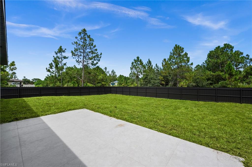 Expansive backyard featuring a manicured lawn, a concrete patio, and a dark privacy fence