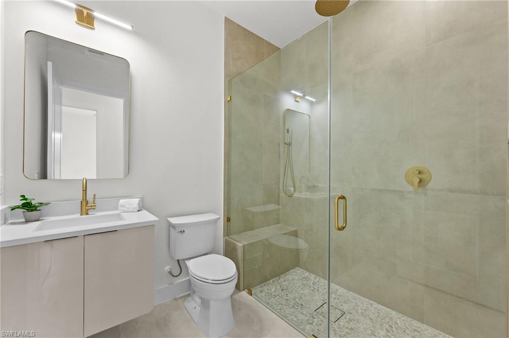 Modern bathroom featuring a frameless glass shower enclosure with a rain shower head and pebble-tiled floor