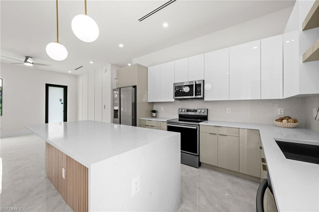 Modern kitchen featuring a large white island with slatted wood-finish paneling, white glossy upper cabinetry, and beige lower cabinetry
