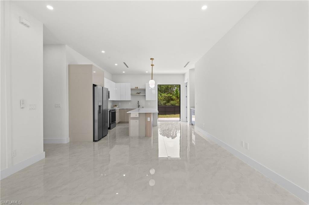 Open-concept interior featuring light tile flooring and recessed lighting