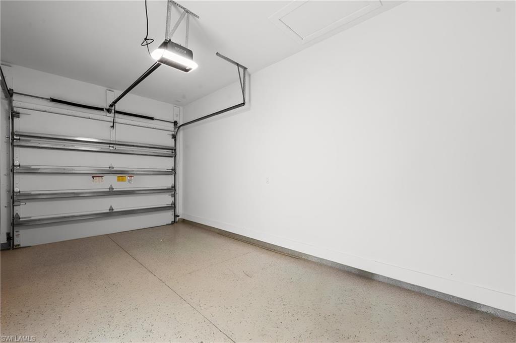 Spacious garage featuring an automatic overhead door, overhead lighting, and concrete flooring
