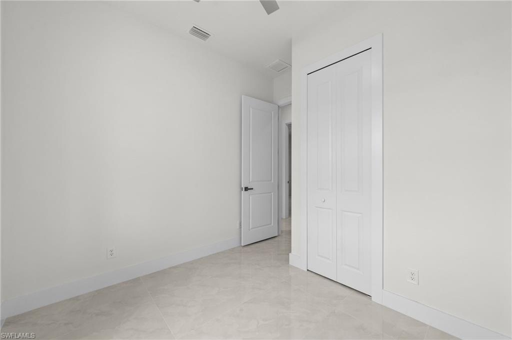 Neutral-toned room featuring light-colored tile flooring, white walls, and a bi-fold closet door