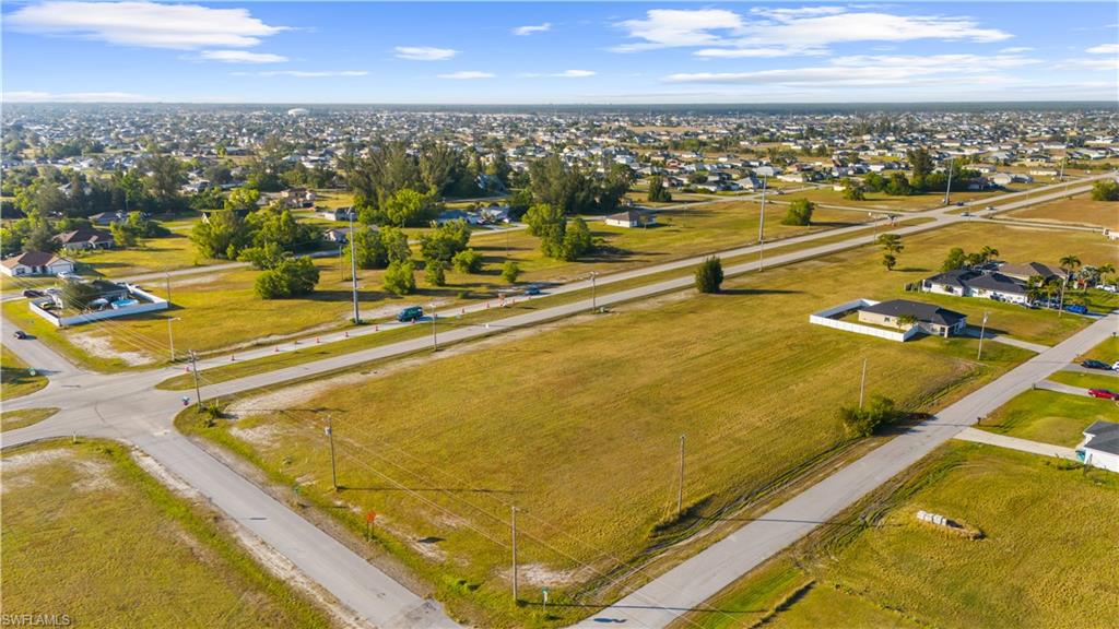 Expansive undeveloped lot featuring a clear, level terrain with scattered mature trees and paved road frontage
