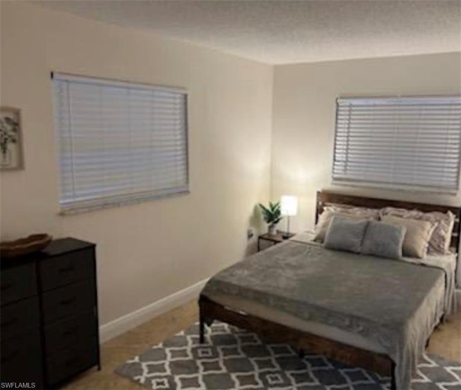 Bedroom with baseboards and light carpet