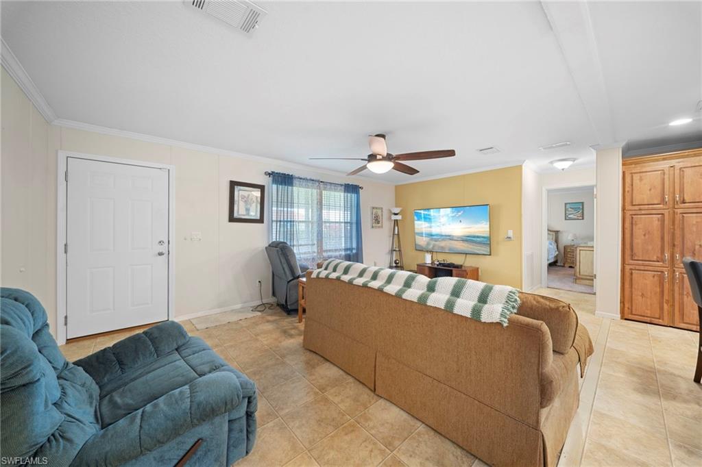 Living area featuring tile flooring, a ceiling fan with integrated lighting, and a prominent accent wall