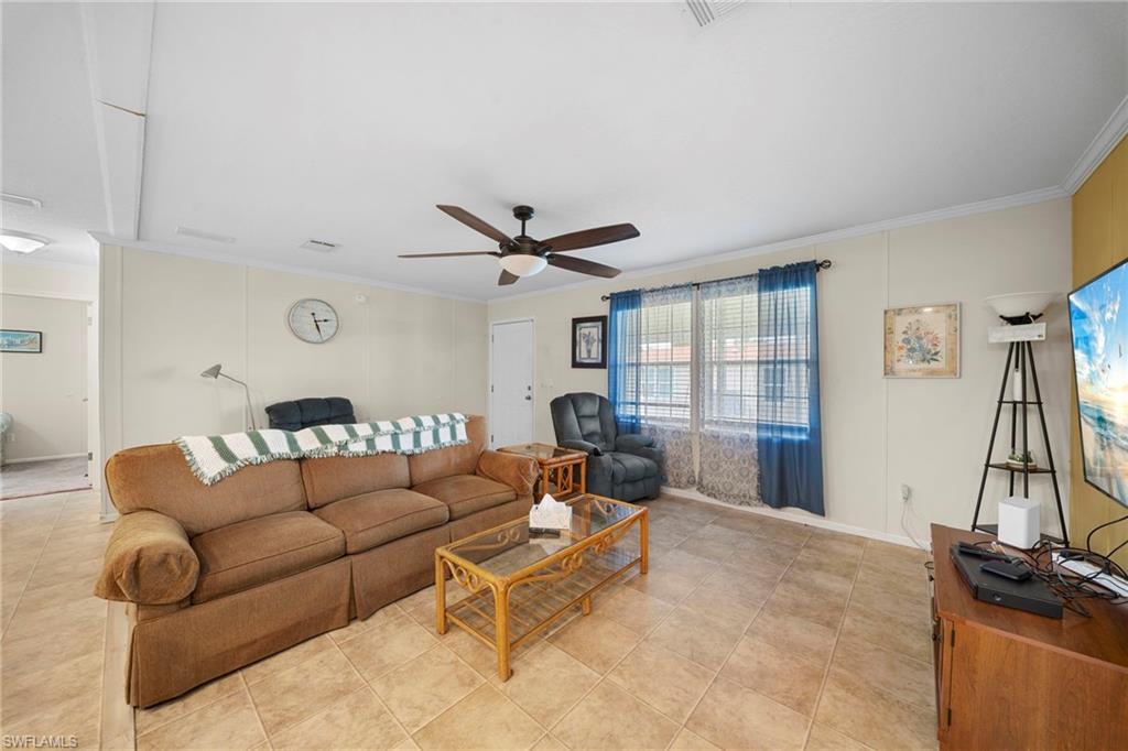 Spacious living area featuring tile flooring, neutral wall tones, and crown molding