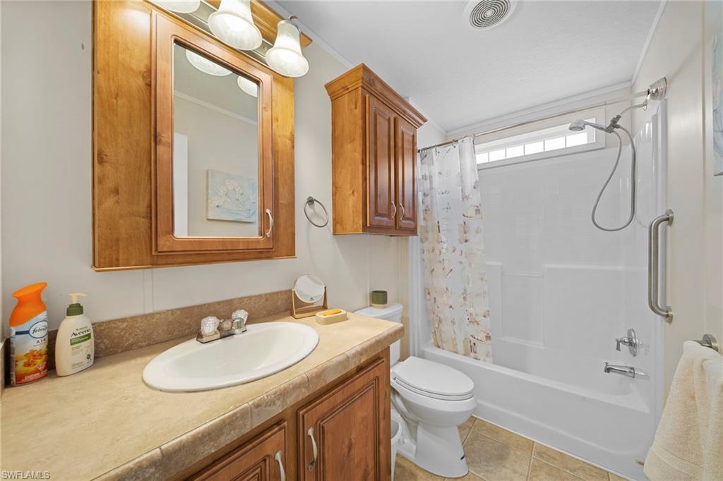 Bathroom featuring a light wood-finish vanity with a single basin, a matching mirrored medicine cabinet, and overhead sconce lighting