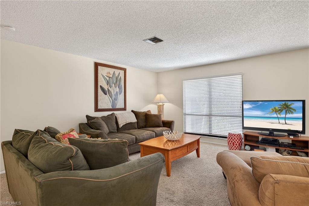 Living area featuring light colored carpet and a textured ceiling