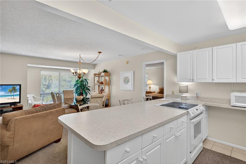 Kitchen with open floor plan, white appliances, white cabinets, light countertops, and a chandelier