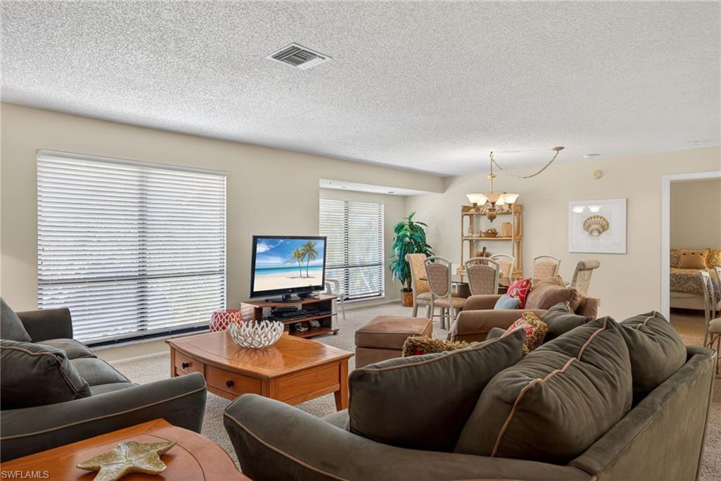 Living area with a chandelier, a textured ceiling, and carpet floors