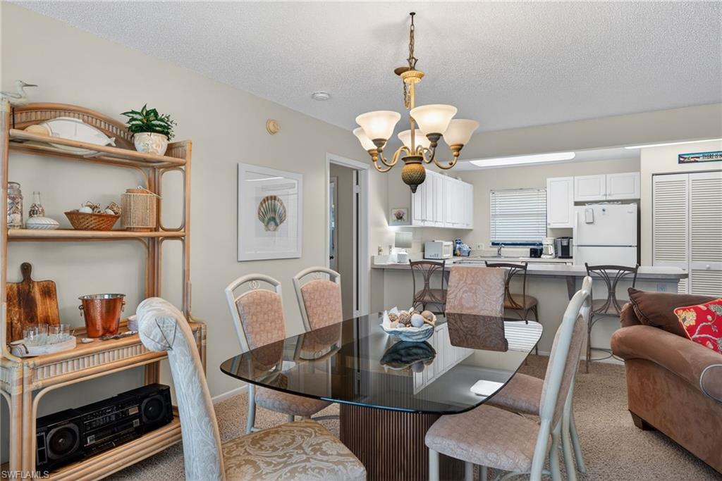 Dining space featuring light carpet, a textured ceiling, and a chandelier