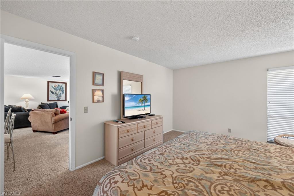 Primary bedroom with light colored carpet and a textured ceiling