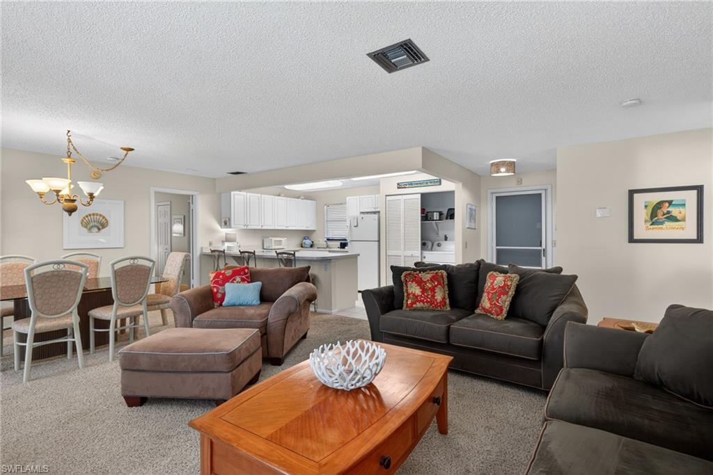 Living room with a chandelier, a textured ceiling, and light colored carpet