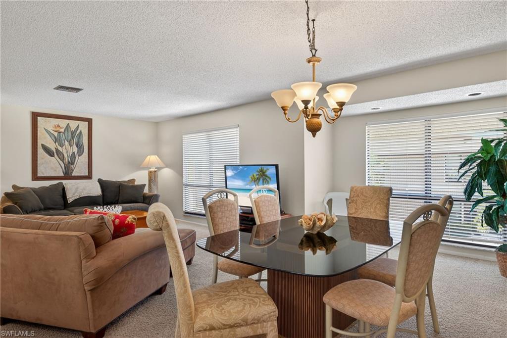 Carpeted dining area featuring a textured ceiling and a chandelier