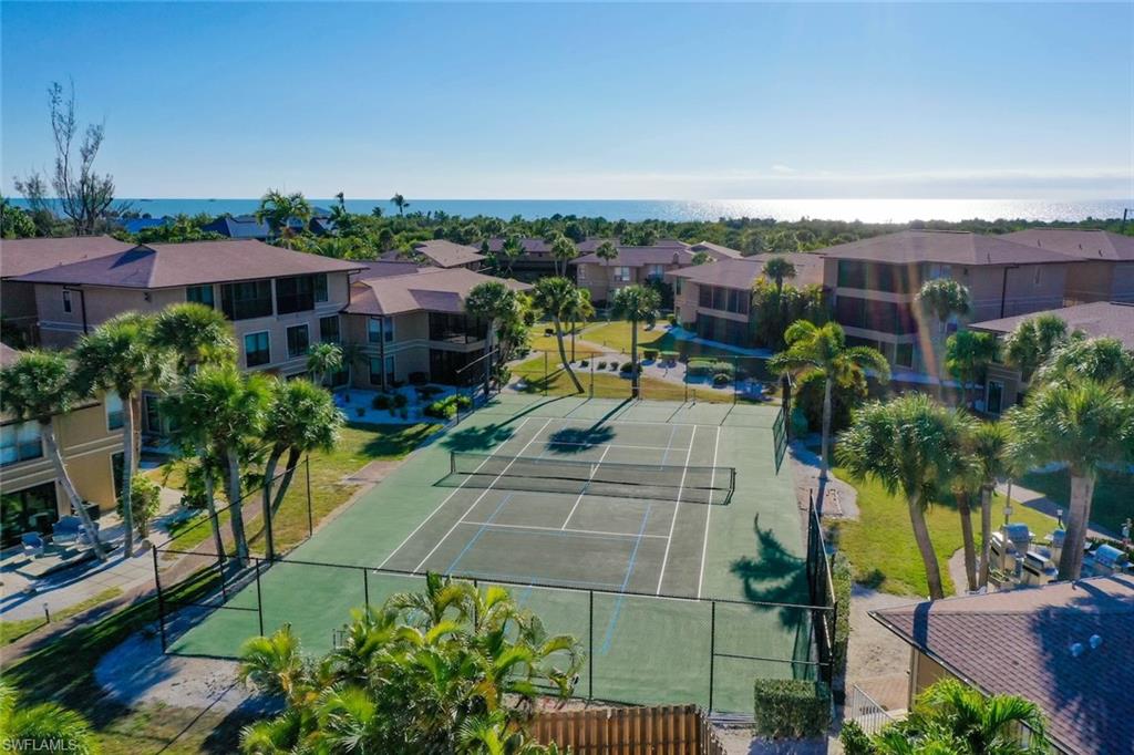 View of tennis court with a patio area