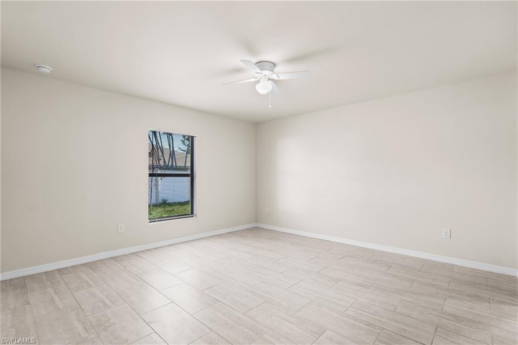 Spacious room with light-toned tile flooring, neutral wall paint, and a ceiling fan