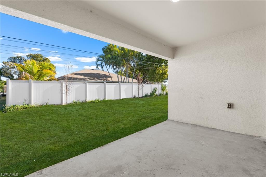 Covered patio with a concrete slab, leading to a vibrant green lawn