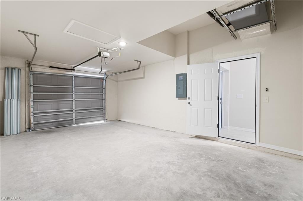 Spacious garage featuring a concrete floor, overhead lighting, and a panel garage door