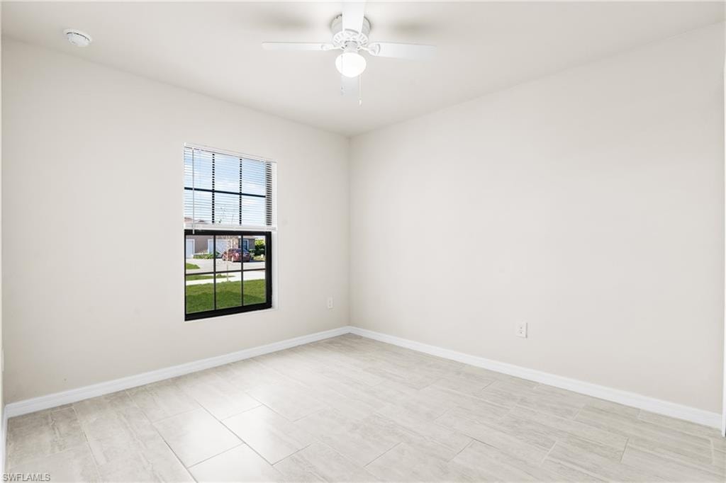 Neutral-toned room featuring light-colored tile flooring, white baseboards, and a window with white blinds