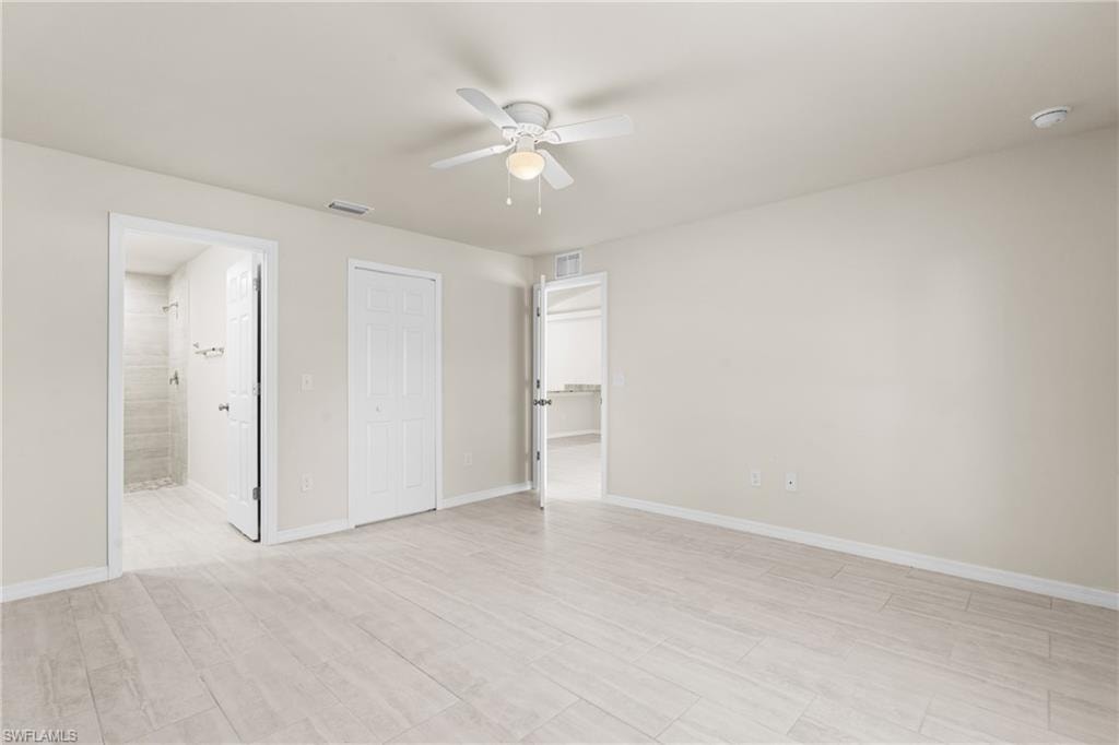 Spacious room featuring wood-finish tile flooring, neutral wall tones, and a ceiling fan with integrated lighting