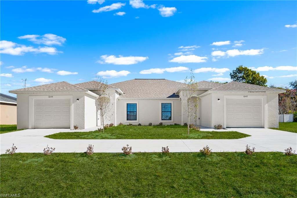Duplex residence featuring stucco exterior, individual garage access for each unit, and a shared, curved concrete driveway