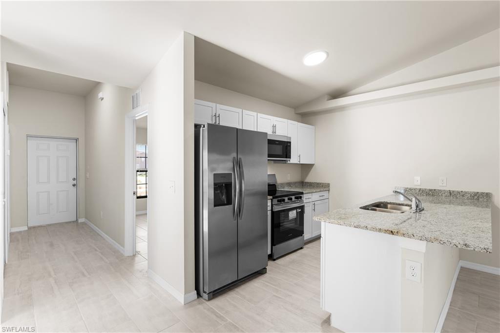Kitchen featuring granite countertops, stainless steel appliances, white cabinetry, and a circular ceiling light fixture