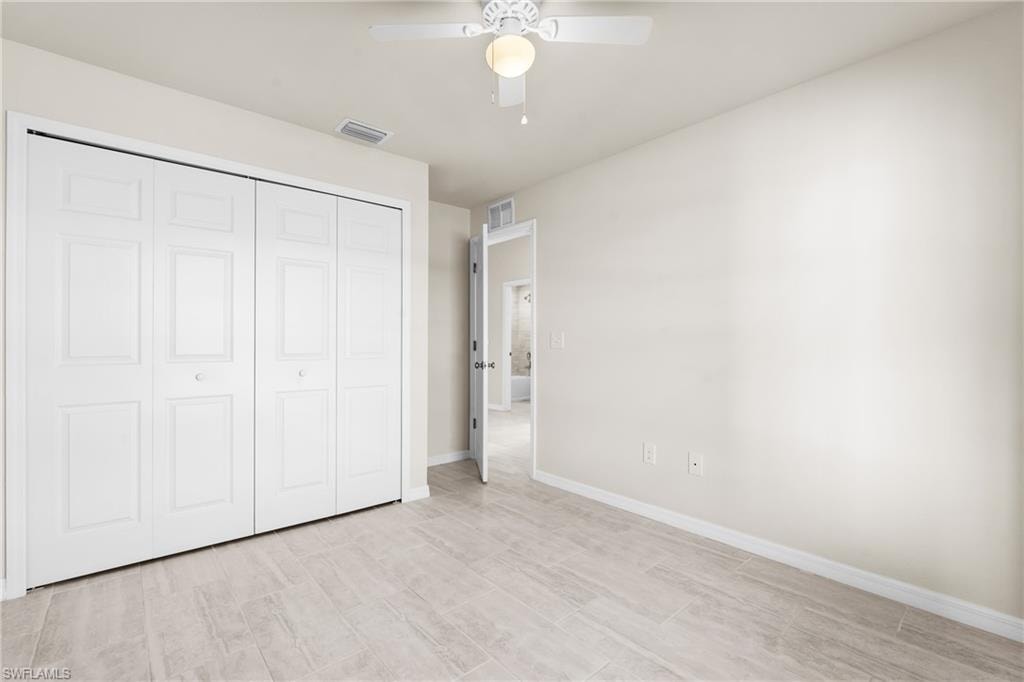 Neutral-toned interior room featuring wood-look tile flooring, white baseboards, and a ceiling fan with integrated lighting