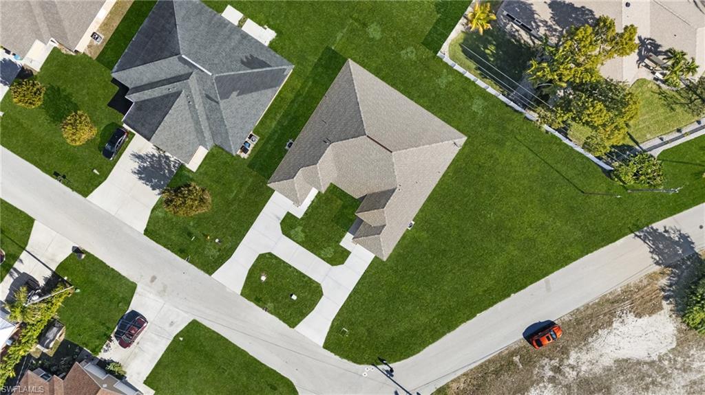 Aerial view showcasing a property with a large, L-shaped concrete driveway