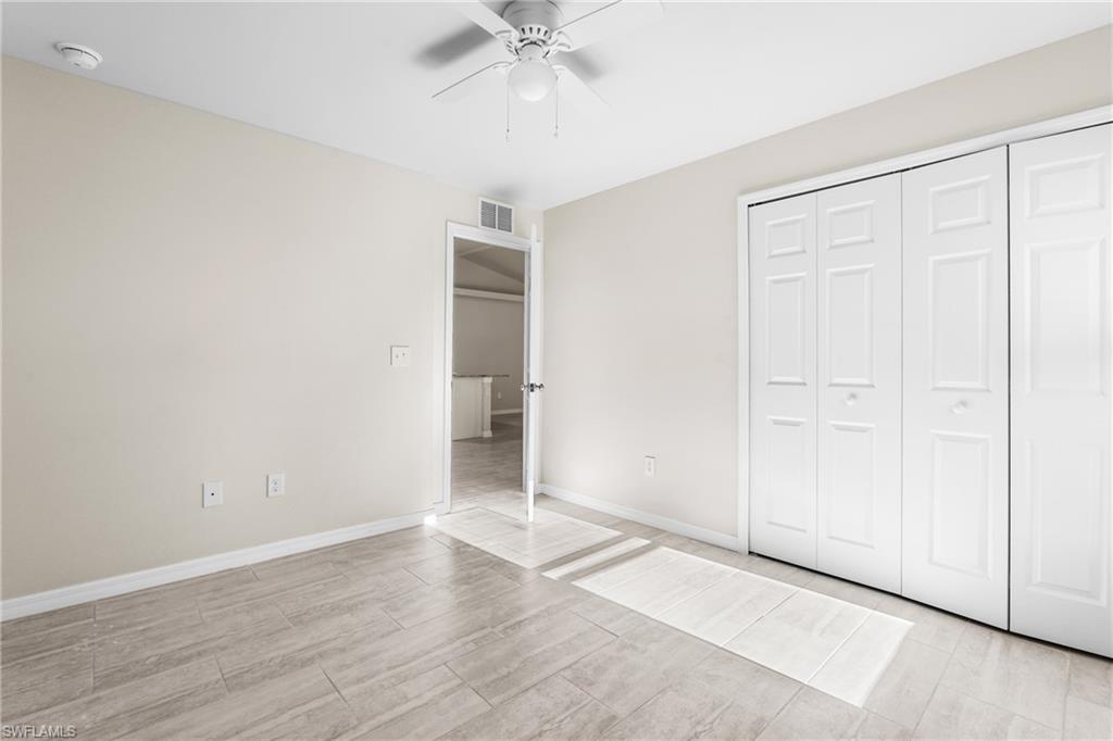 Bedroom featuring light beige wall paint, light-toned wood-finish flooring, and a ceiling fan with light fixture