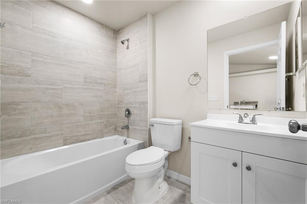 Bathroom featuring a white vanity with integrated sink, chrome fixtures, and a large wall-mounted mirror
