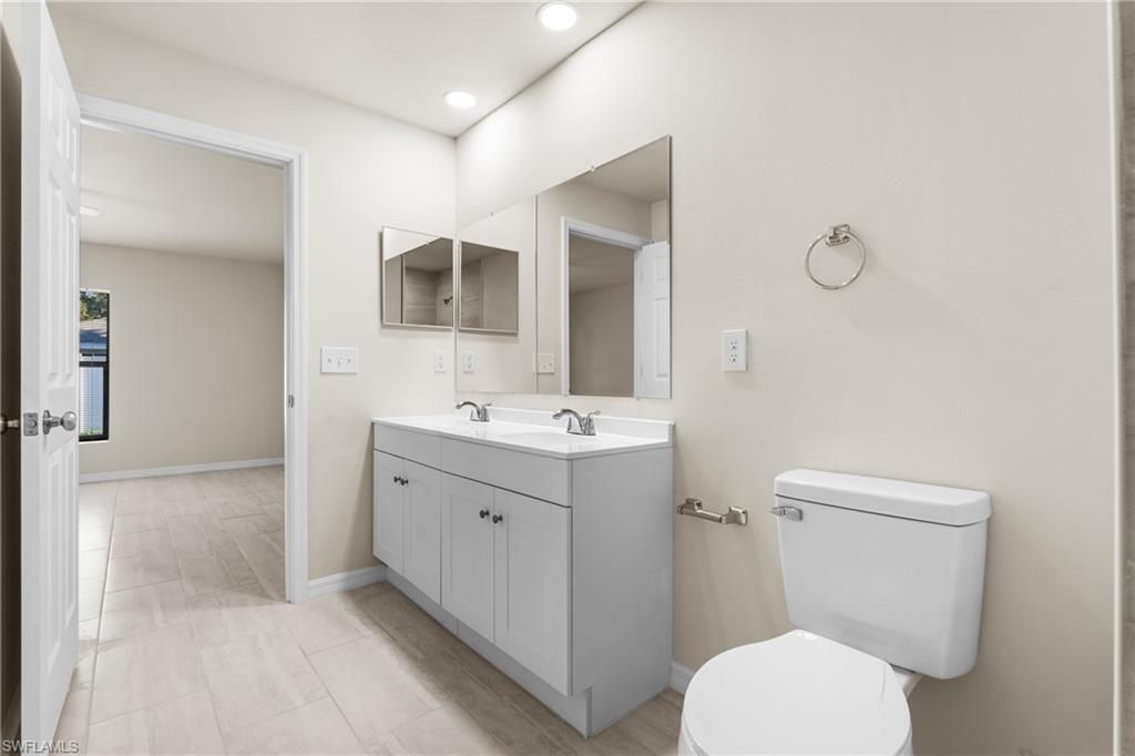 Bathroom featuring a double vanity with white cabinetry, a dual-sink countertop, and two framed mirrors
