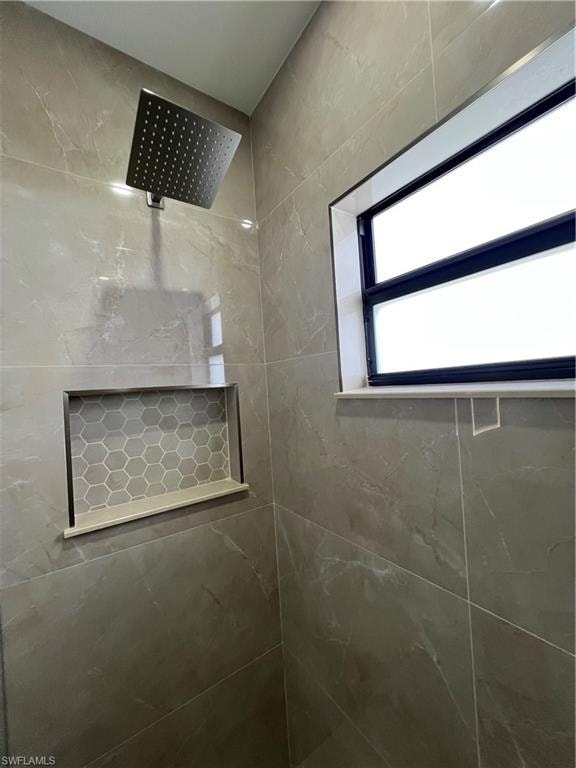 Shower stall with large format gray-toned tile, featuring a square rain showerhead
