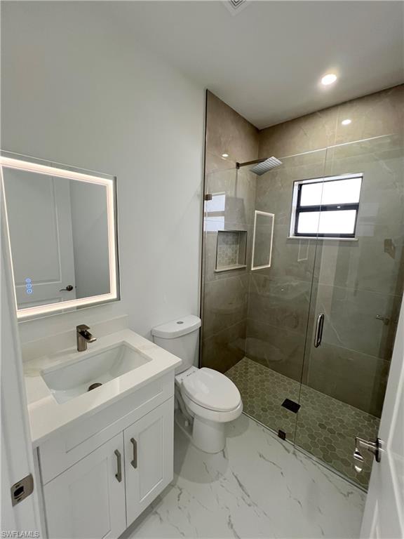 2nd bathroom featuring a glass-enclosed shower with a rainfall showerhead and tiled walls