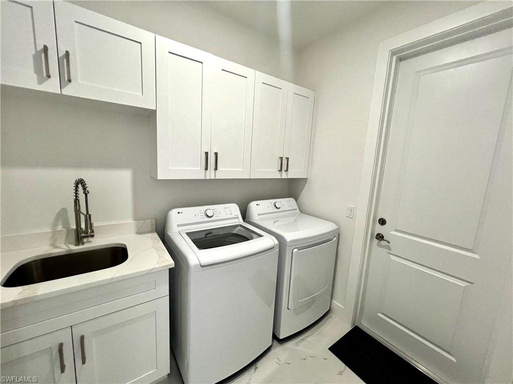 Dedicated laundry space featuring white shaker-style cabinetry, a built-in sink with a gooseneck faucet, and light-toned countertop